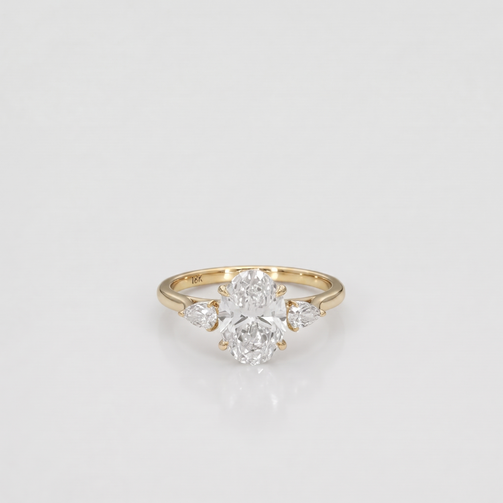 A yellow gold ring featuring a central oval diamond surrounded by two marquise-cut diamonds on the sides, set against a clean white background.