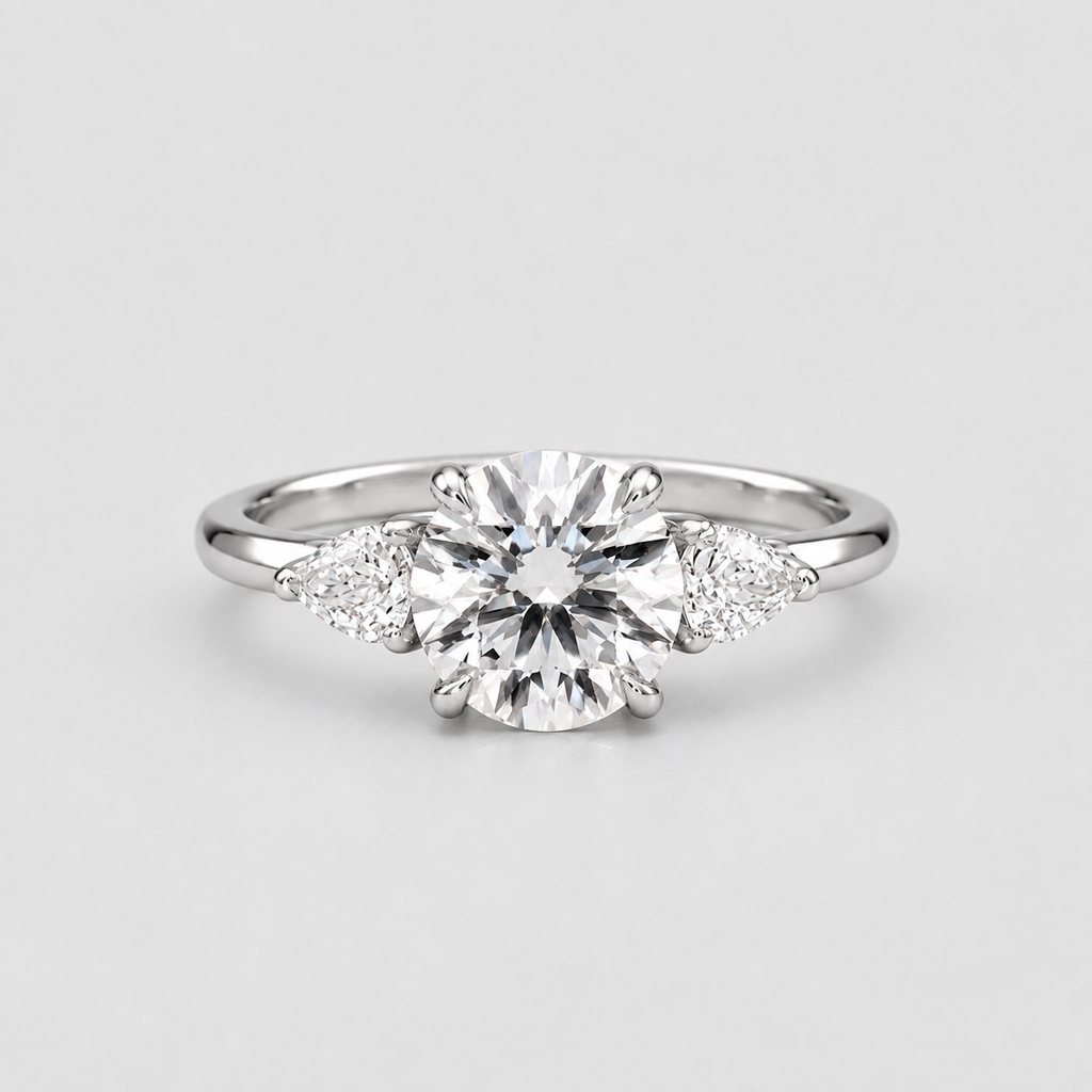 A silver engagement ring featuring a round brilliant-cut center stone with two small round side stones and two marquise-cut side stones, set on a plain light gray background.