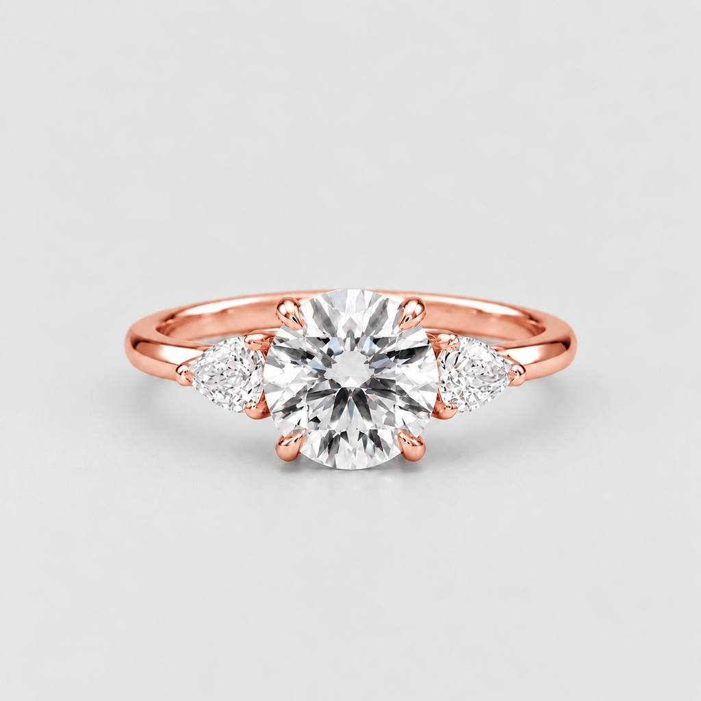 A rose gold engagement ring featuring a round brilliant-cut center stone and two marquise-cut side stones, set on a polished band against a light gray background.