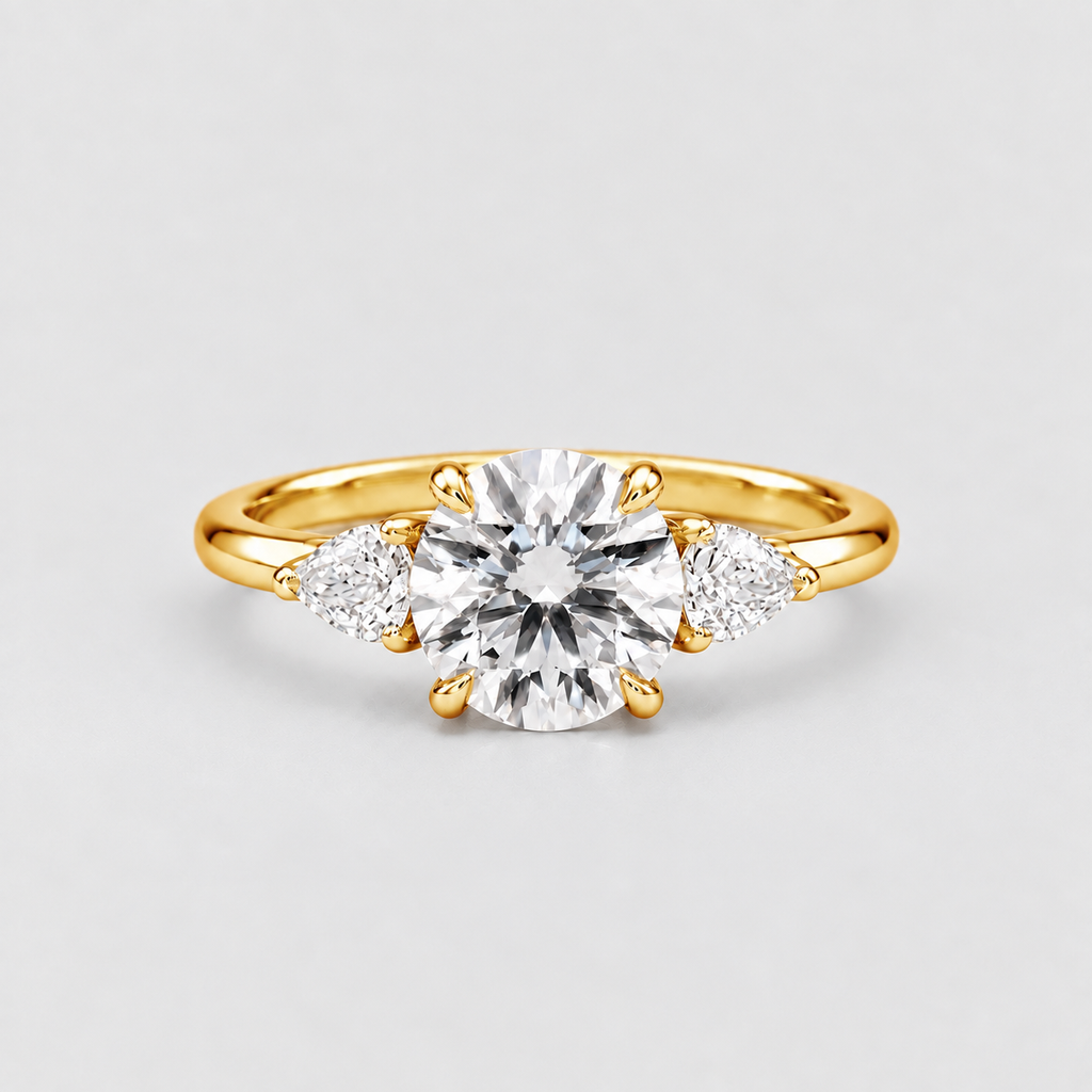 A yellow gold three-stone engagement ring featuring a round brilliant-cut center diamond flanked by two smaller round diamonds on a light gray background.