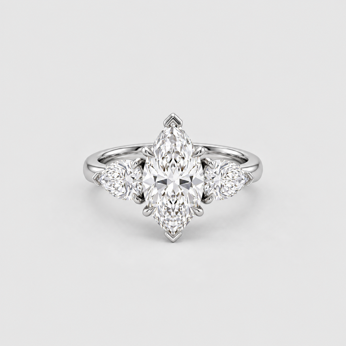 A silver-toned diamond ring featuring a marquise-cut center stone with three smaller round diamonds flanking it, set against a light gray background.