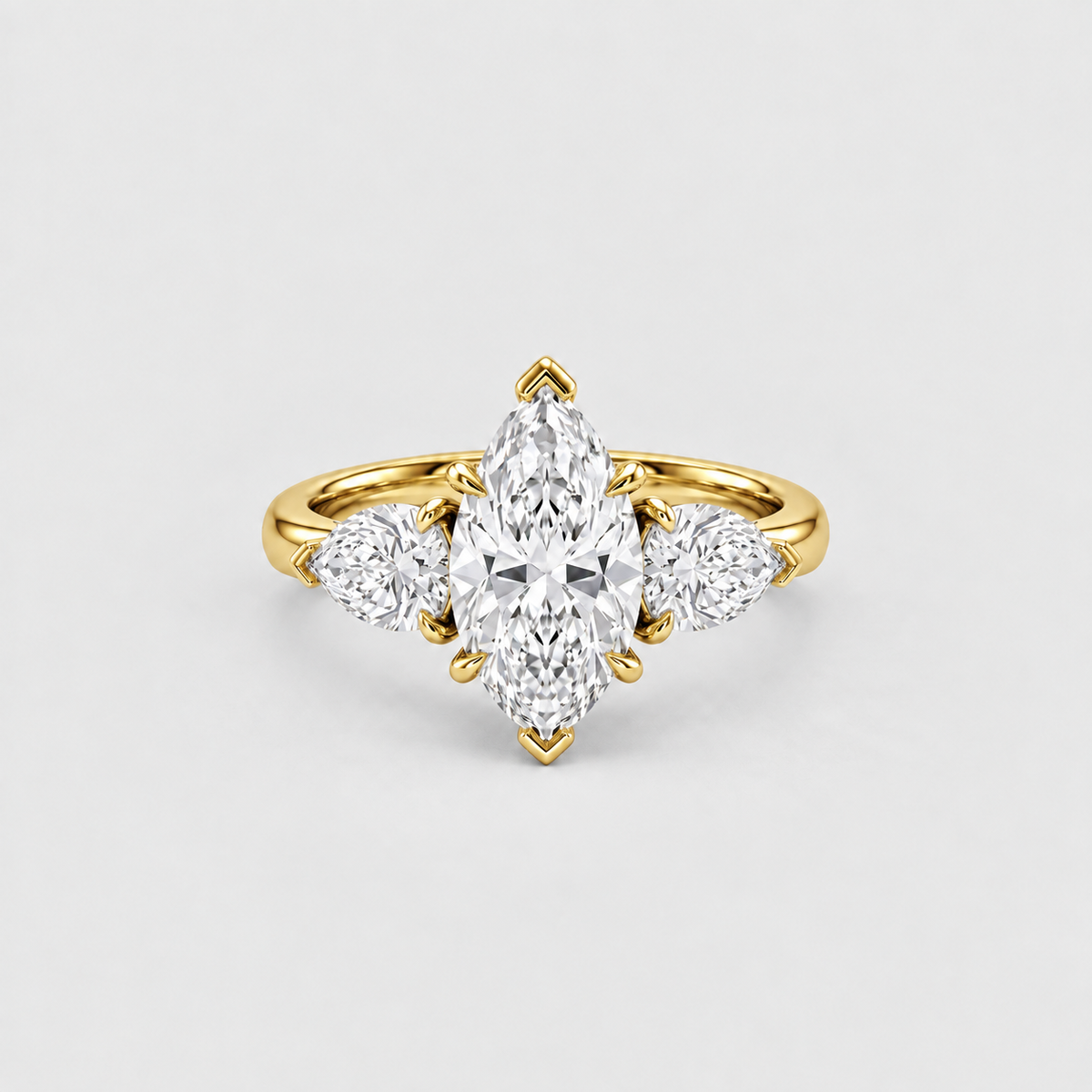 A yellow gold ring featuring a marquise-cut center diamond flanked by two round diamonds, set against a clean light gray background.