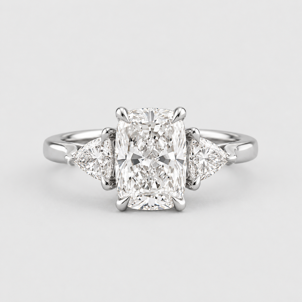 A radiant cut diamond engagement ring with triangular side diamonds on a polished silver-colored band, shown against a light gray background.