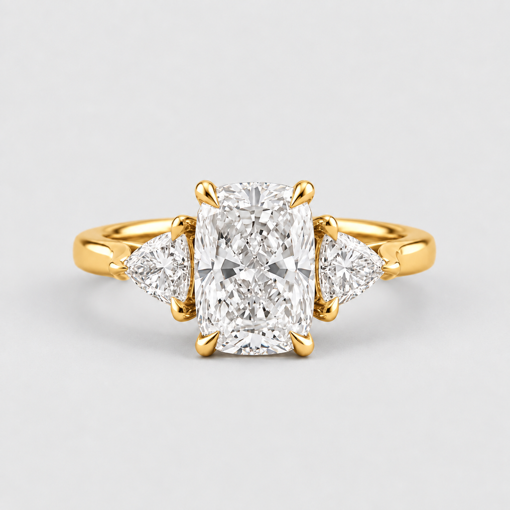 A yellow gold three-stone ring featuring a large rectangular radiant-cut center diamond flanked by two smaller pear-cut diamonds, set on a light gray background.