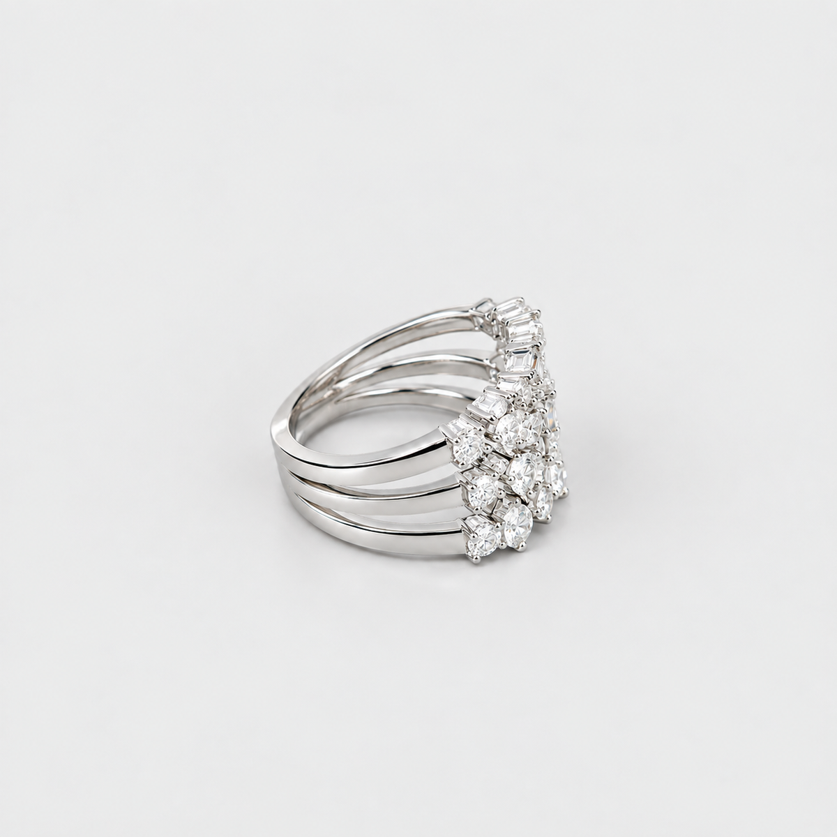 A silver-toned multi-band ring featuring a floral cluster of clear gemstones on the front, photographed on a clean light gray background.
