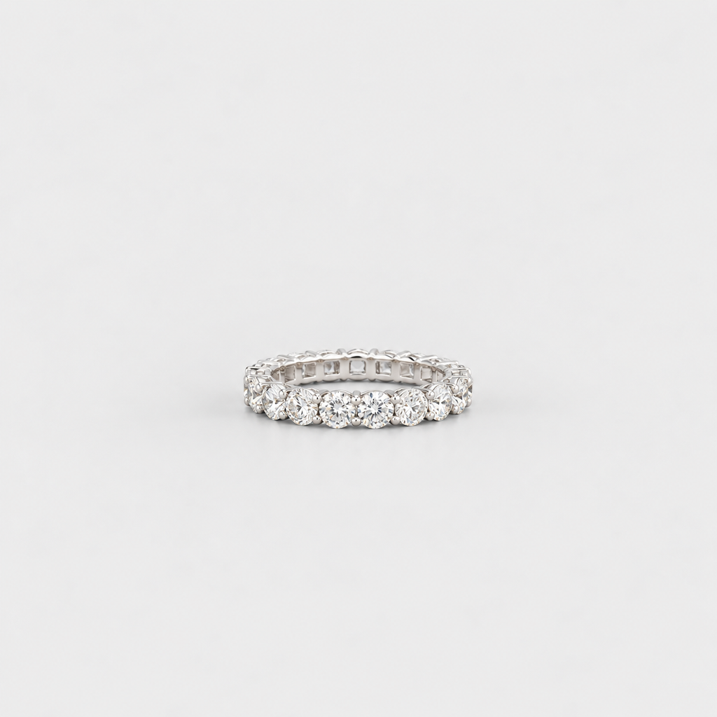 A silver-tone eternity ring set with round brilliant-cut diamonds, photographed on a seamless light gray background.