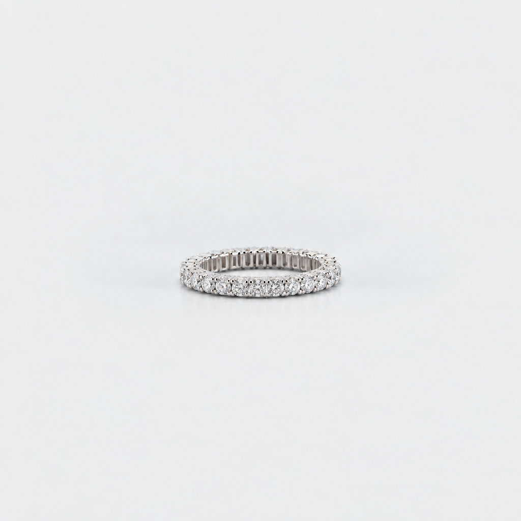A slim silver eternity ring paved with small round-cut clear stones, centered on a seamless light gray background.