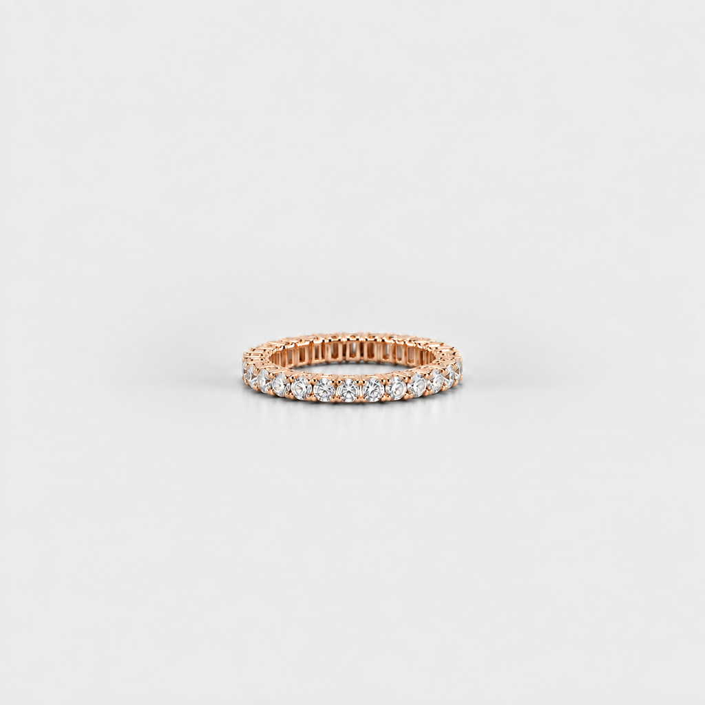A rose gold eternity ring set with round brilliant-cut diamonds, photographed on a clean, light gray background.