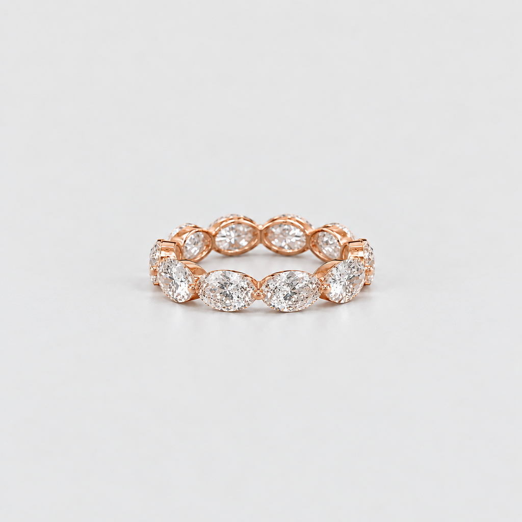 A rose gold eternity ring featuring a row of marquise-cut diamonds, photographed on a clean, light gray background.
