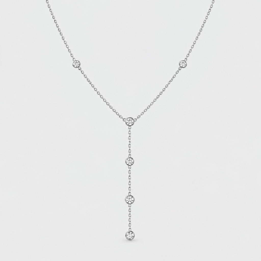 A delicate silver Y-necklace featuring five small, round clear gemstones set along the chain, suspended against a light gray background.
