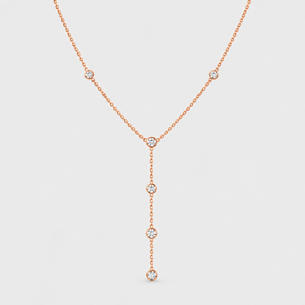 A delicate rose gold Y-necklace featuring five small round-cut clear gemstones set along the chain, displayed against a solid light gray background.