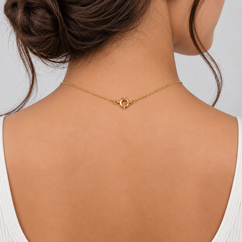 A close-up back view of a woman wearing a delicate gold chain necklace with a small interlocking circle pendant at the center of the neck.