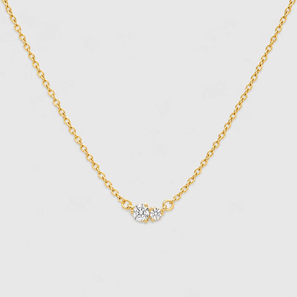 A delicate gold chain necklace featuring a small central cluster of three clear round-cut gemstones in a gold setting, displayed against a light gray background.