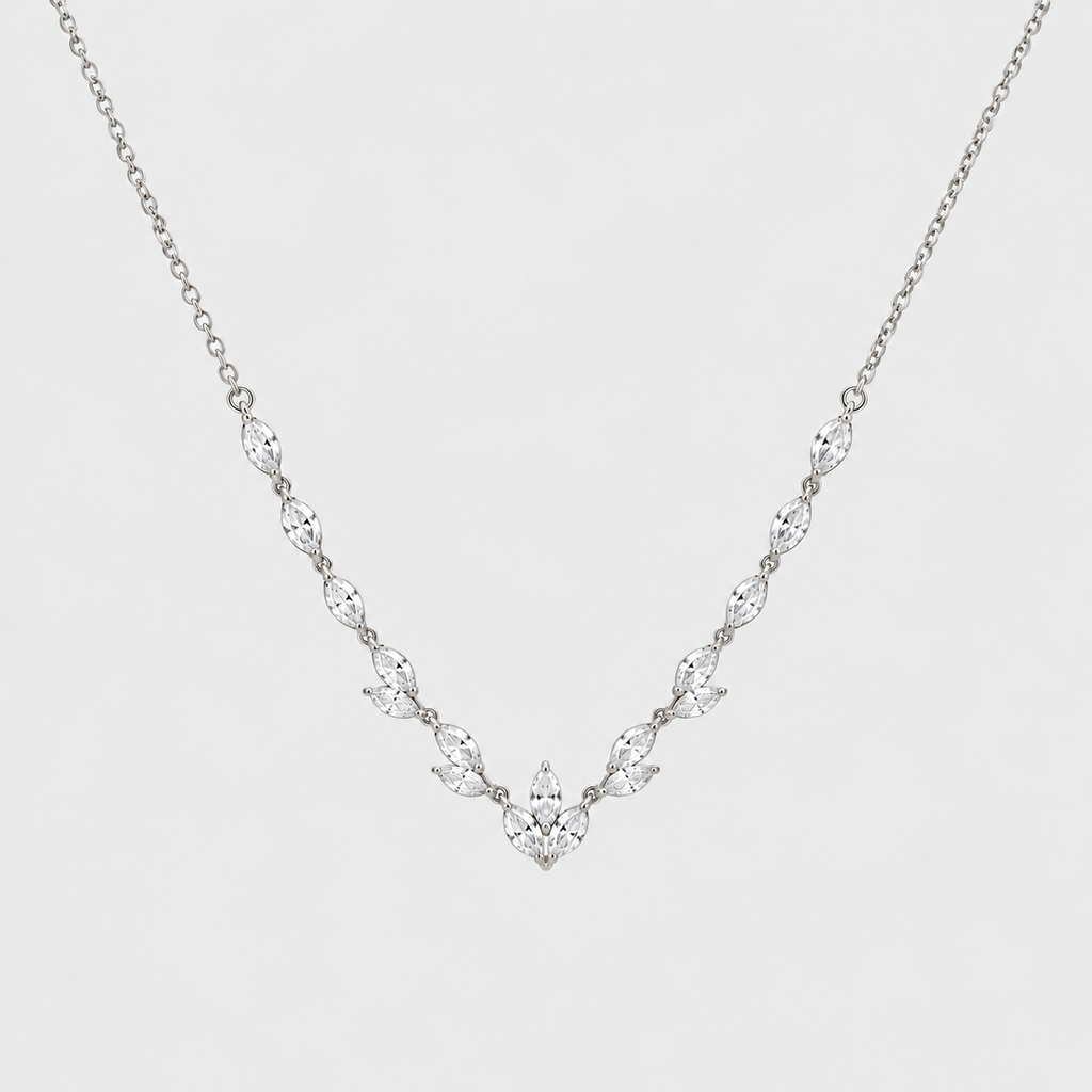 A delicate silver-toned necklace featuring a V-shaped arrangement of marquise-cut clear stones on a fine chain, set against a plain light gray background.