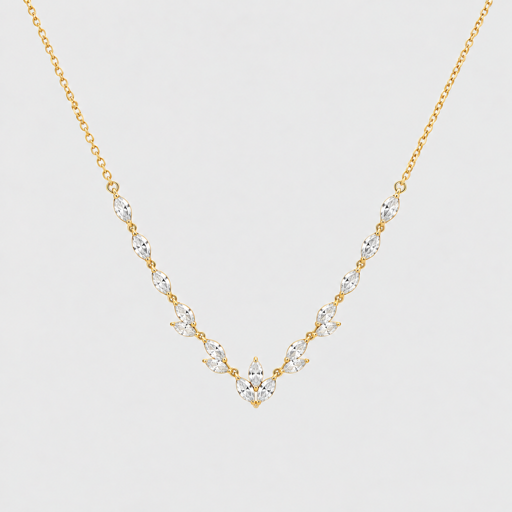 A delicate gold necklace featuring a V-shaped arrangement of marquise-cut clear gemstones on a light gray background.