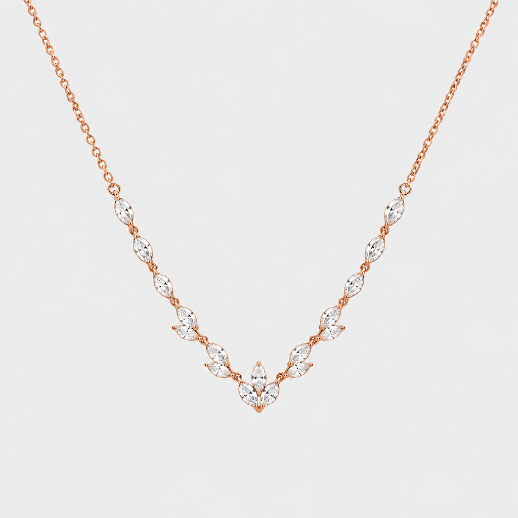 A delicate rose gold necklace featuring a V-shaped arrangement of marquise-cut clear gemstones on a light gray background.