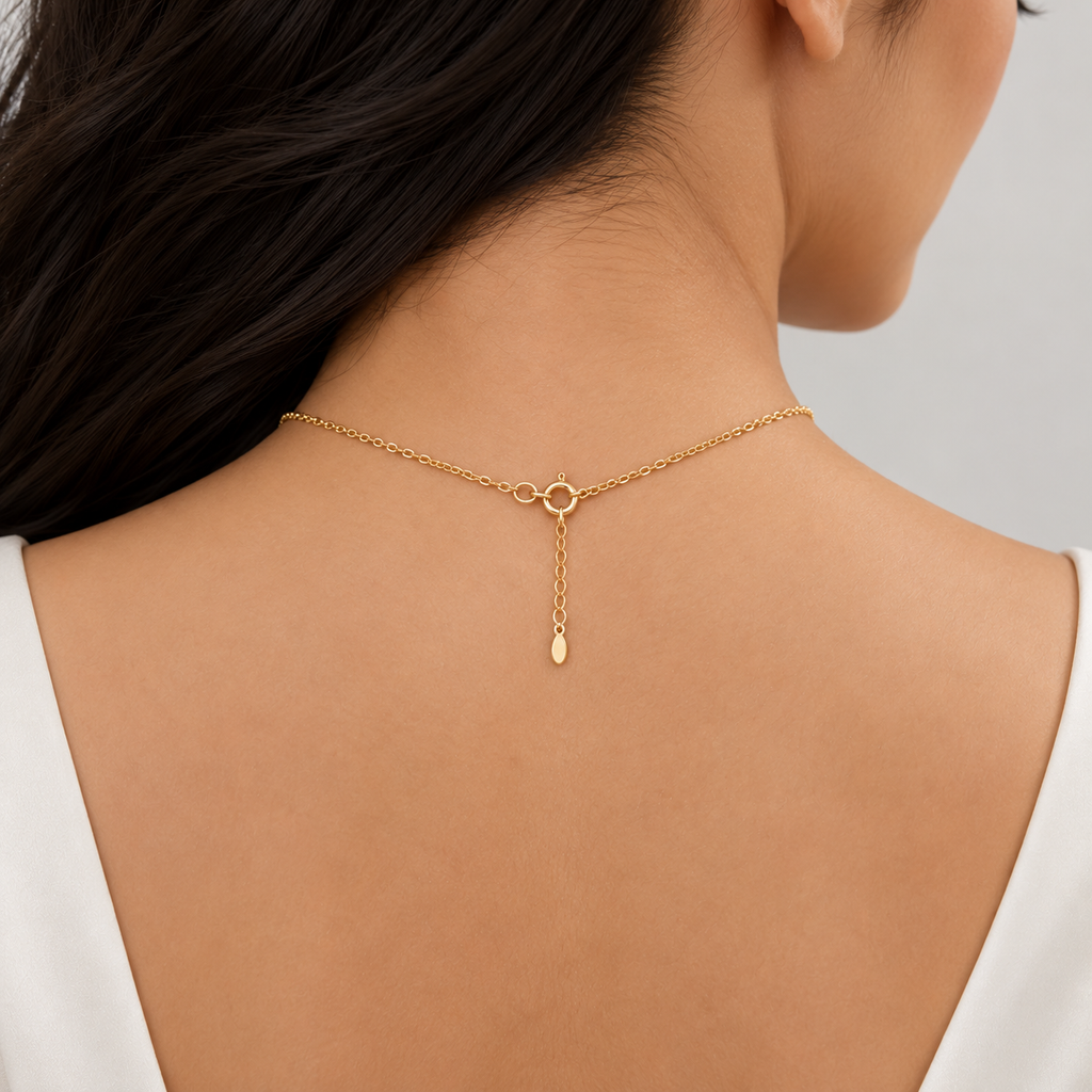 A close-up back view of a woman wearing a delicate gold chain necklace with a small circular ring clasp and a teardrop pendant.