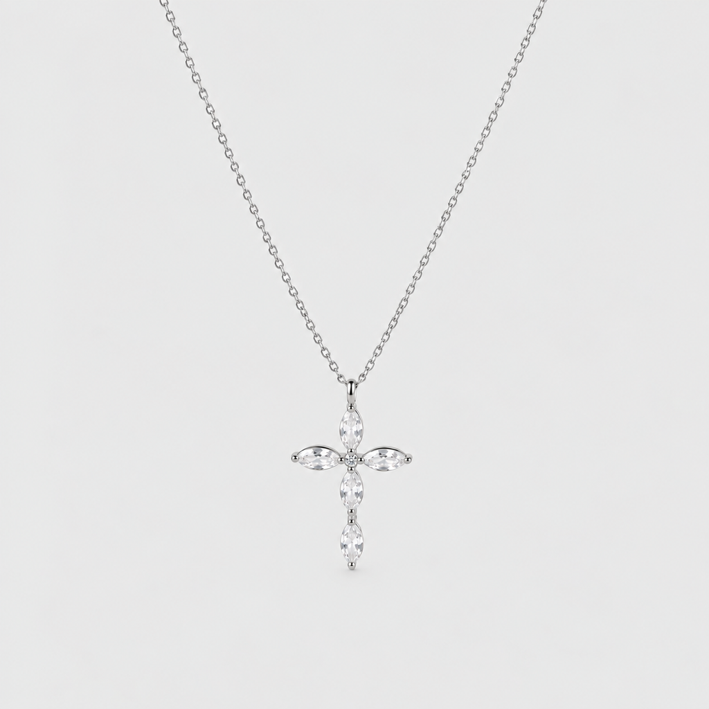 A silver cross pendant necklace adorned with clear marquise-cut and round-cut stones, suspended from a delicate silver chain against a light gray background.