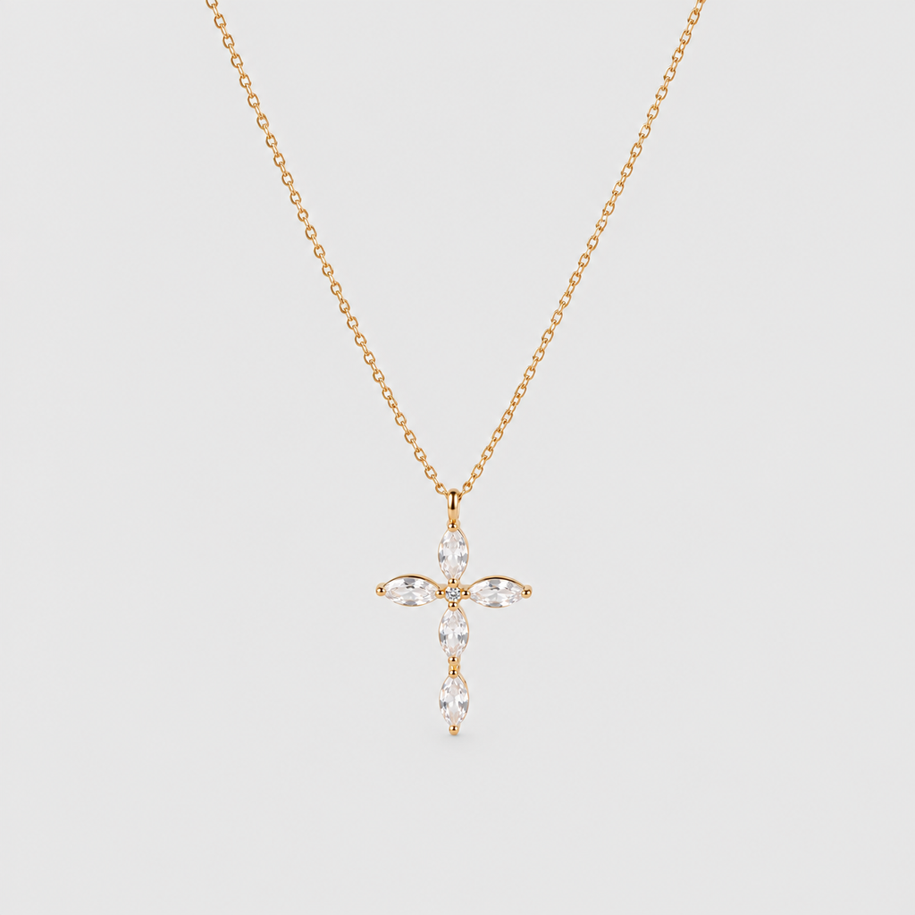 A delicate gold chain necklace with a cross-shaped pendant adorned with marquise-cut clear gemstones, displayed against a solid light gray background.