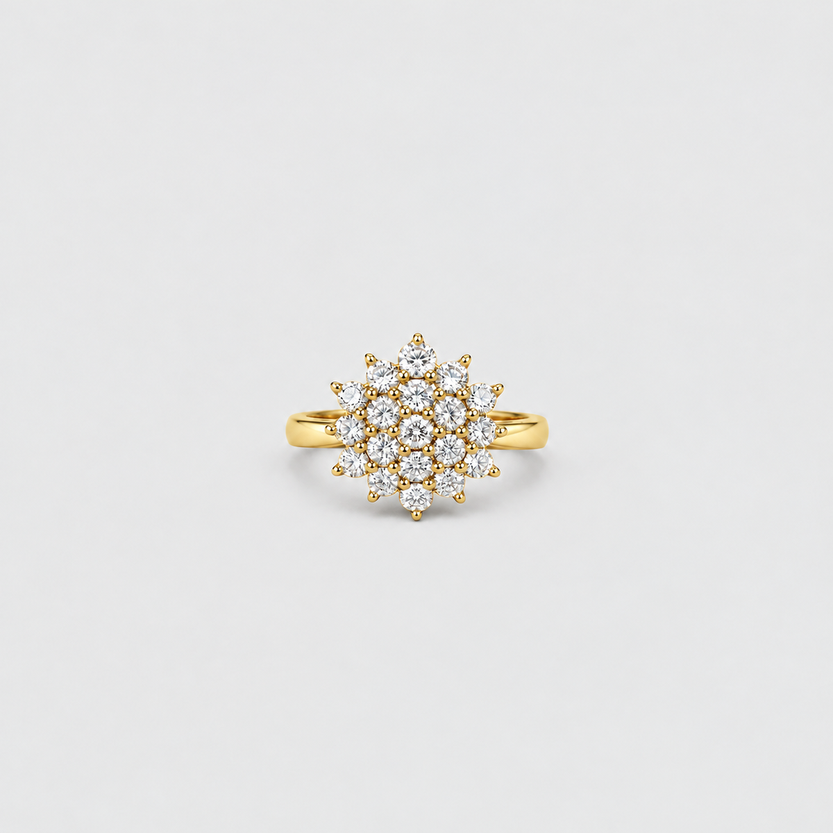 A yellow gold ring featuring a circular cluster of small clear gemstones, photographed against a clean, light gray background.