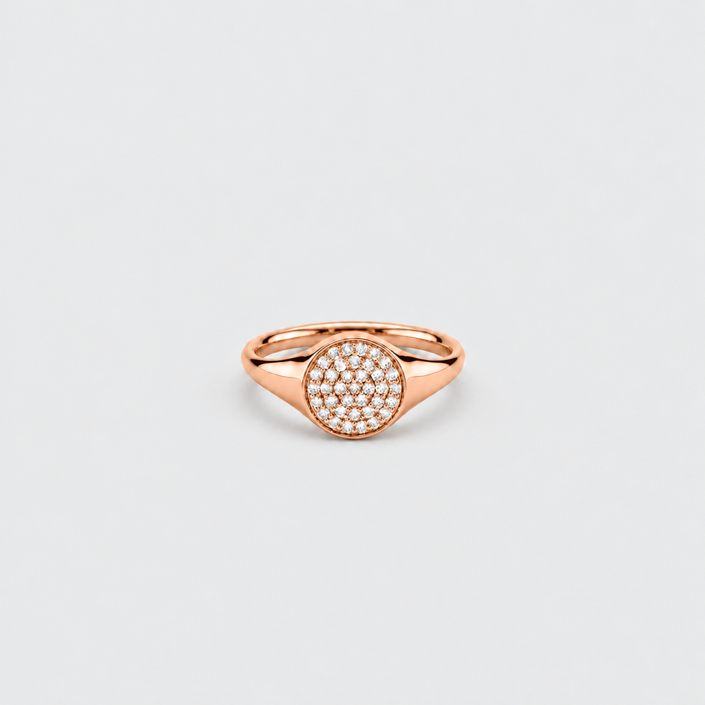 A rose gold signet ring featuring a circular pavé diamond center, shown on a clean light gray background.