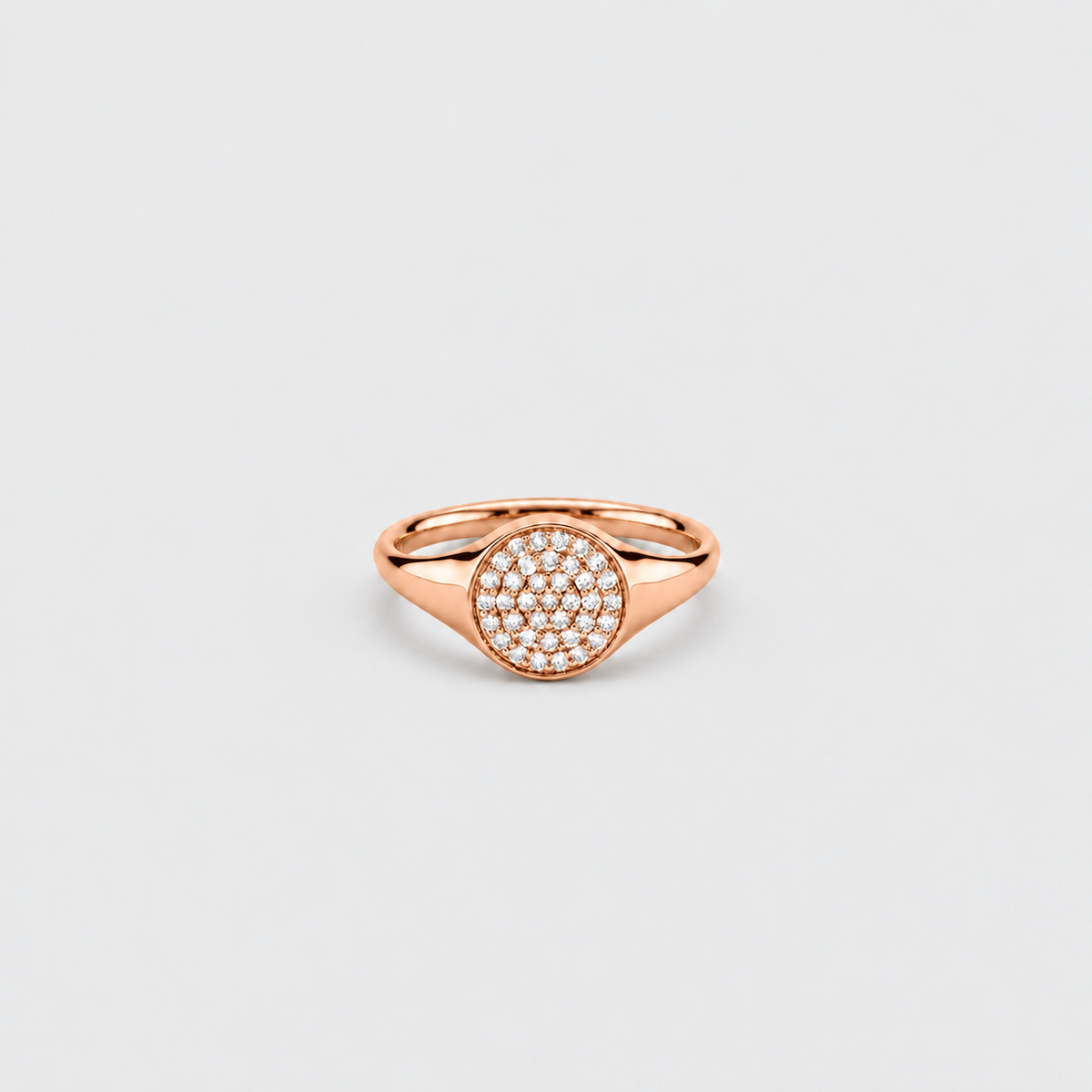 A rose gold signet ring featuring a circular pavé diamond center, shown on a clean light gray background.