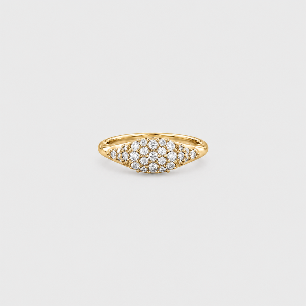 A yellow gold ring featuring a pavé diamond cluster in a marquise-shaped setting, photographed on a clean, light gray background.