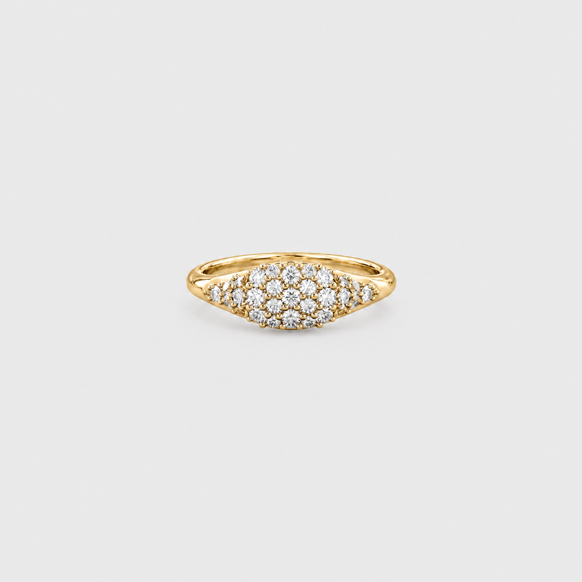 A yellow gold ring featuring a pavé diamond cluster in a marquise-shaped setting, photographed on a clean, light gray background.