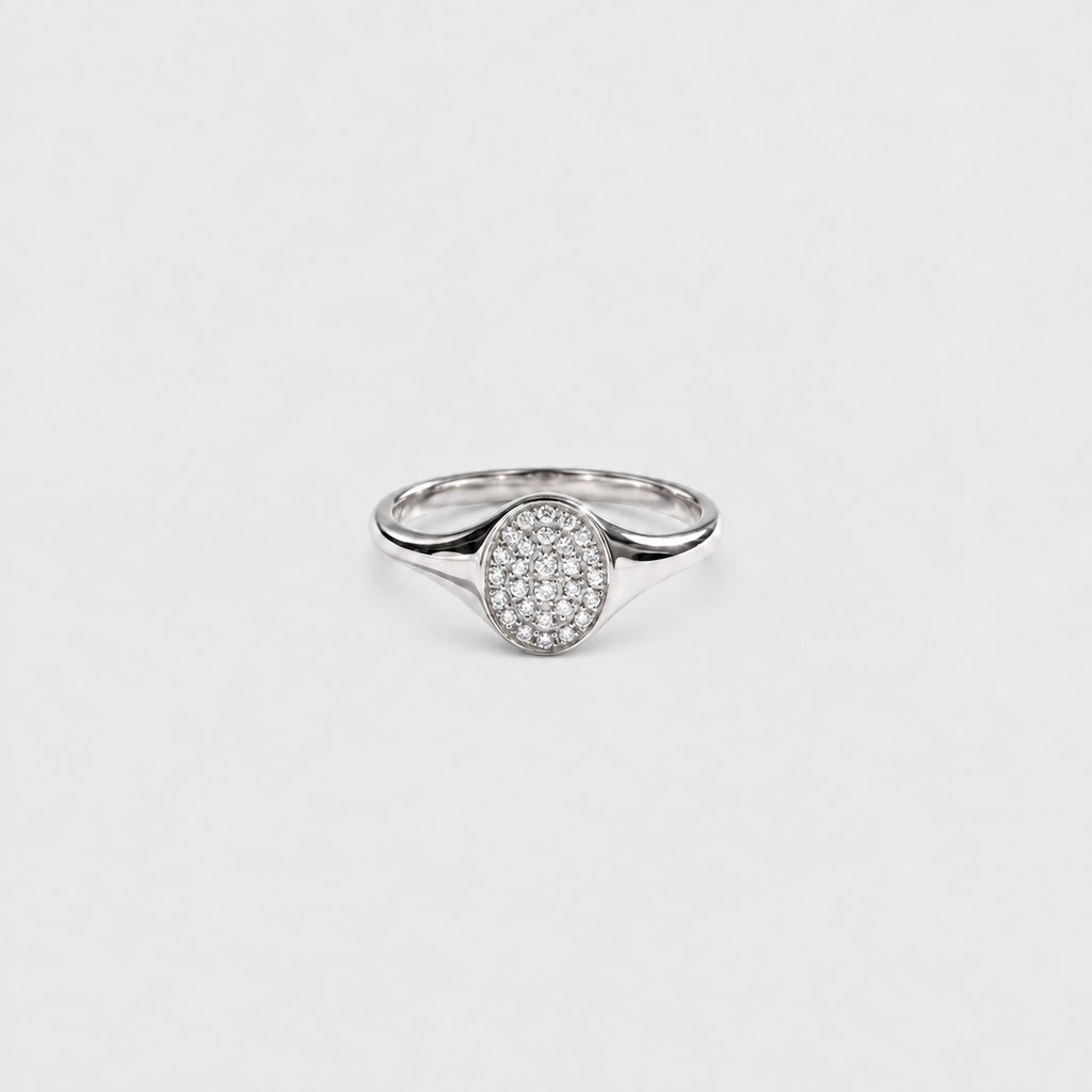 A silver ring with an oval pavé diamond setting on a plain light gray background.