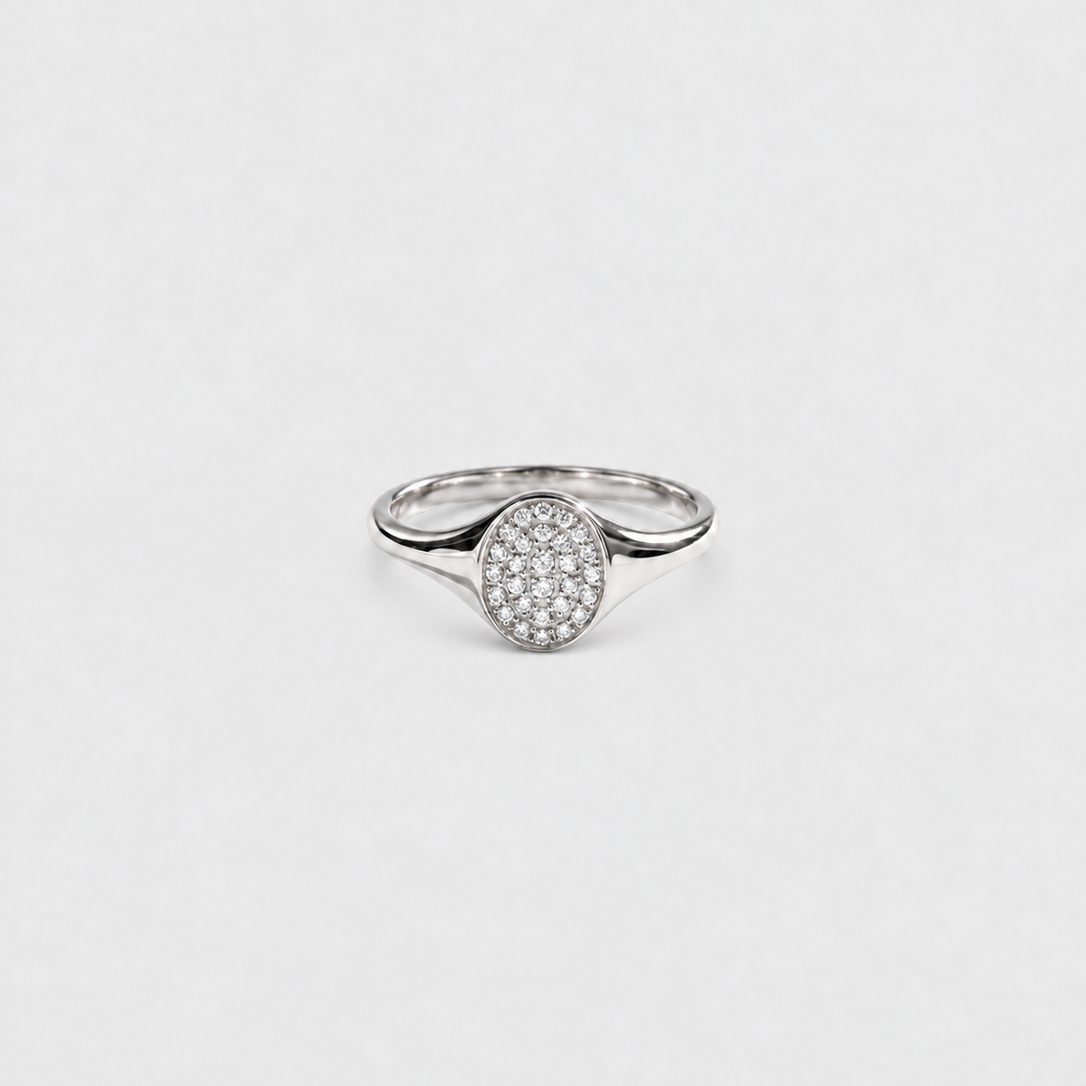 A silver ring with an oval pavé diamond setting on a plain light gray background.
