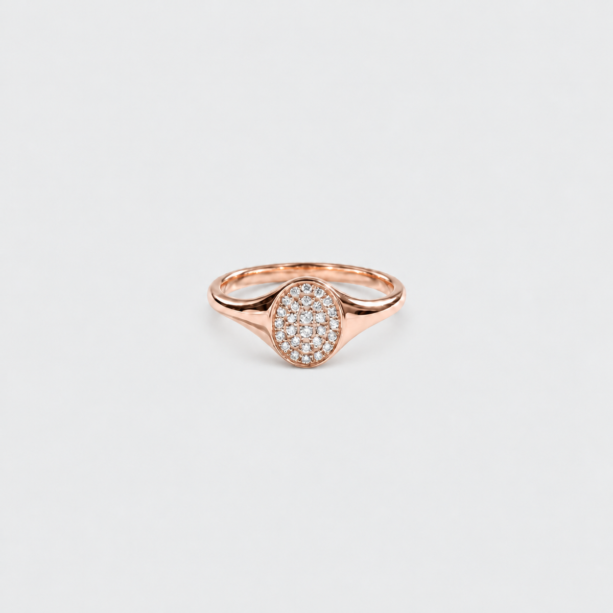 A rose gold ring featuring an oval pavé diamond setting on a clean, light gray background.