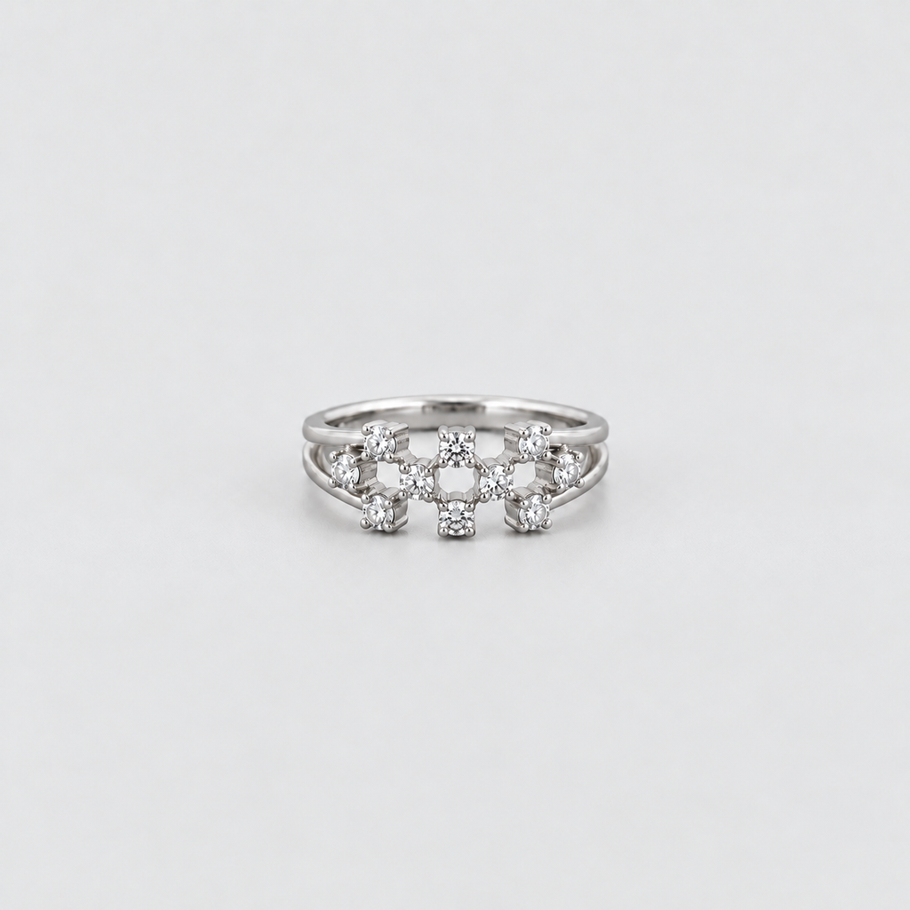 A silver ring featuring a decorative cluster of small clear gemstones in a floral or starburst pattern, photographed on a clean light gray background.