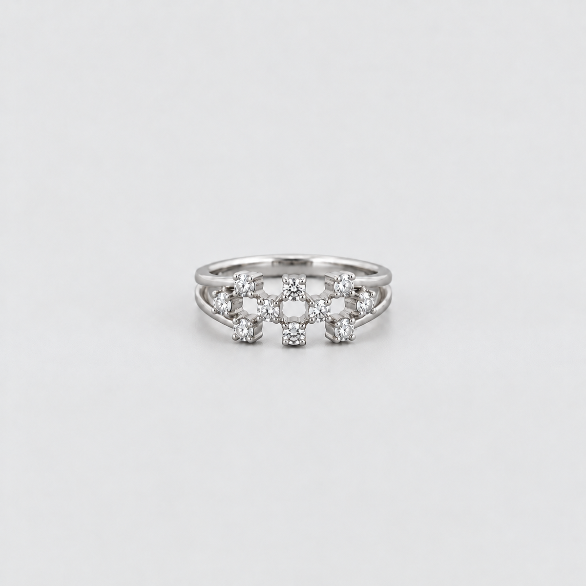 A silver ring featuring a decorative cluster of small clear gemstones in a floral or starburst pattern, photographed on a clean light gray background.