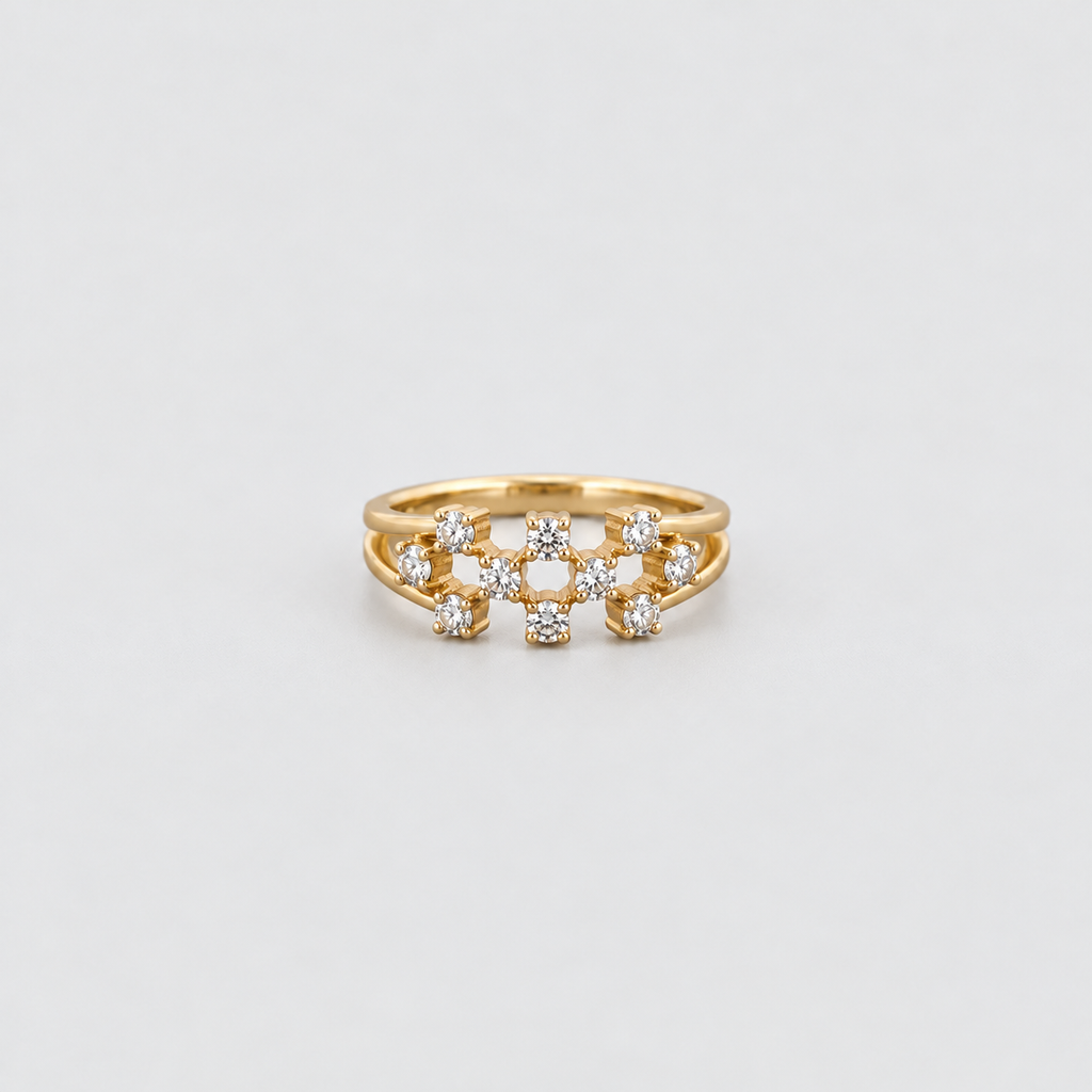 A gold ring with a central cluster of small clear gemstones, photographed on a clean light gray background.