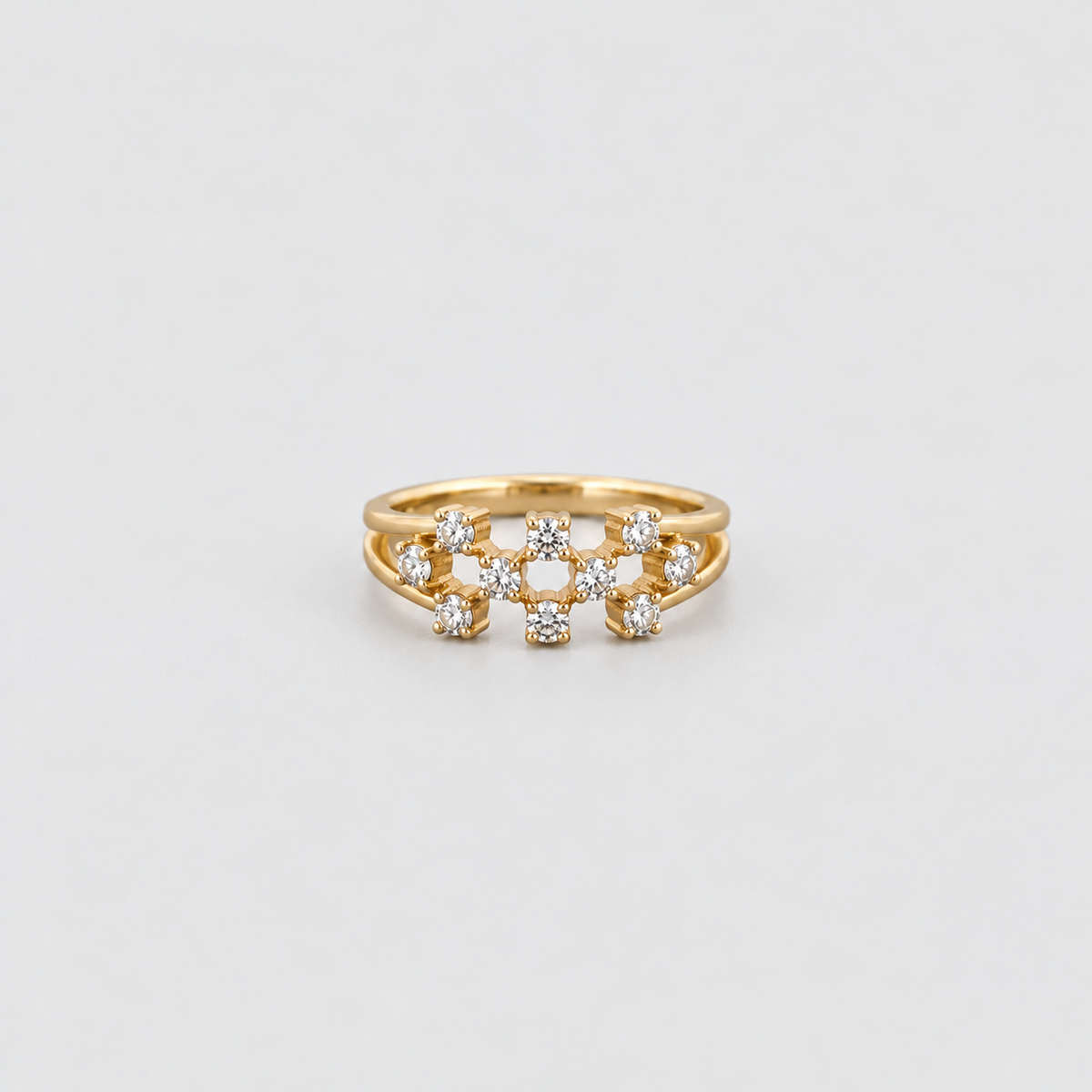 A gold ring with a central cluster of small clear gemstones, photographed on a clean light gray background.
