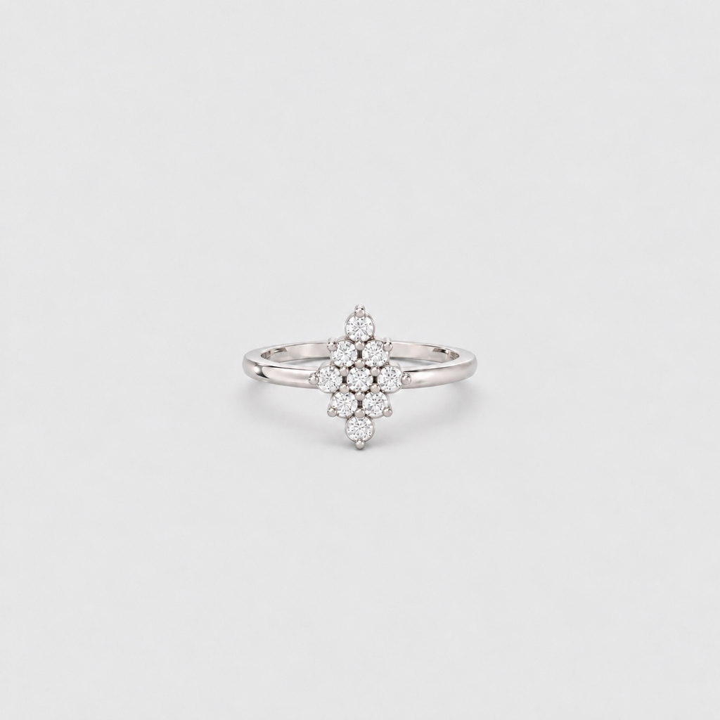 A silver-toned ring featuring a central cluster of small clear gemstones arranged in a floral or starburst pattern, set on a plain light gray background.
