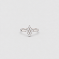 A silver-toned ring featuring a central cluster of small clear gemstones arranged in a floral or starburst pattern, set on a plain light gray background.