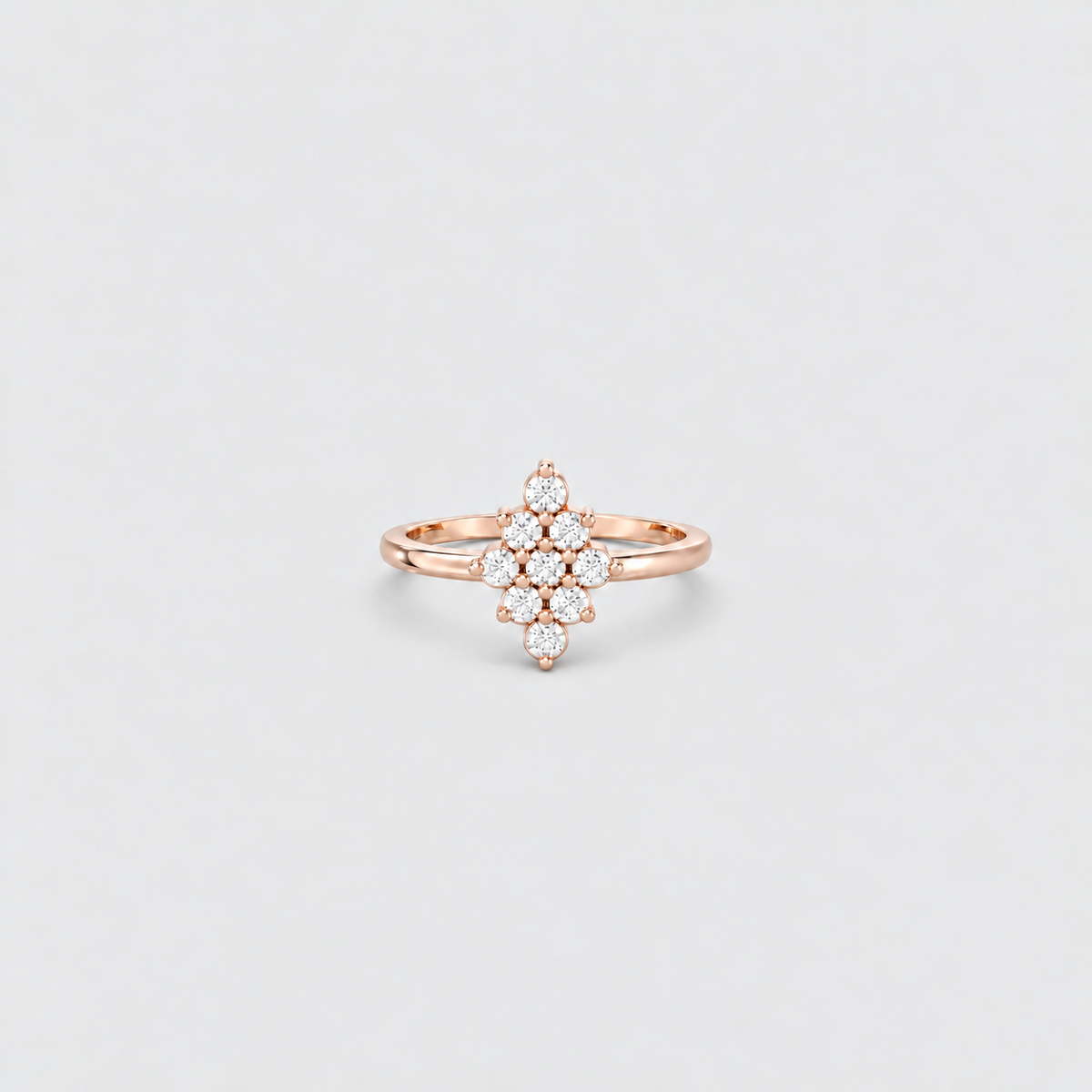 A rose gold ring with a floral cluster setting of small clear stones, centered on a light gray background.