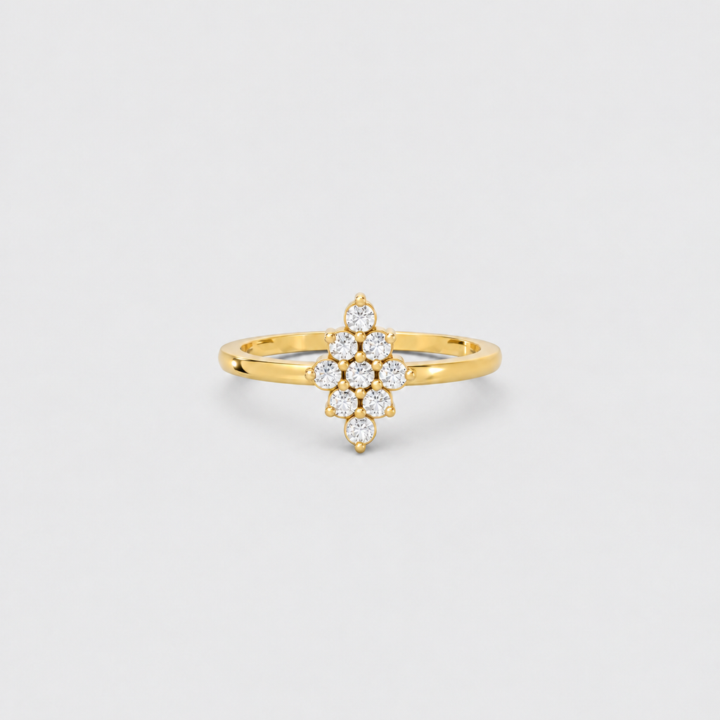 A yellow gold ring featuring a central floral cluster of small round-cut clear gemstones, photographed on a clean light gray background.