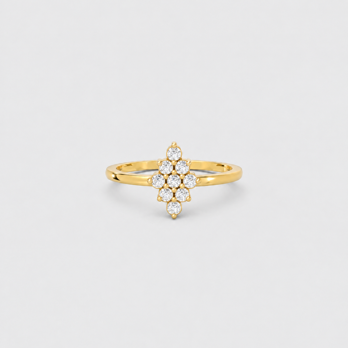 A yellow gold ring featuring a central floral cluster of small round-cut clear gemstones, photographed on a clean light gray background.