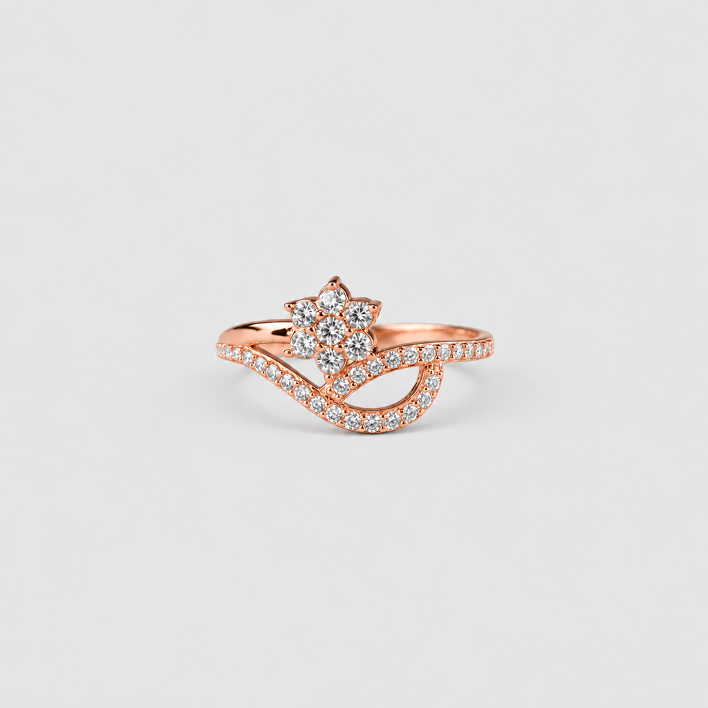 A rose gold ring with a flower-shaped cluster of clear stones and a wavy pavé band, shown on a light gray background.