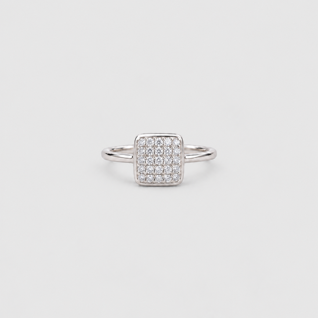 A silver square pavé ring with a pave-set diamond center and a slim band, shown on a light gray background.