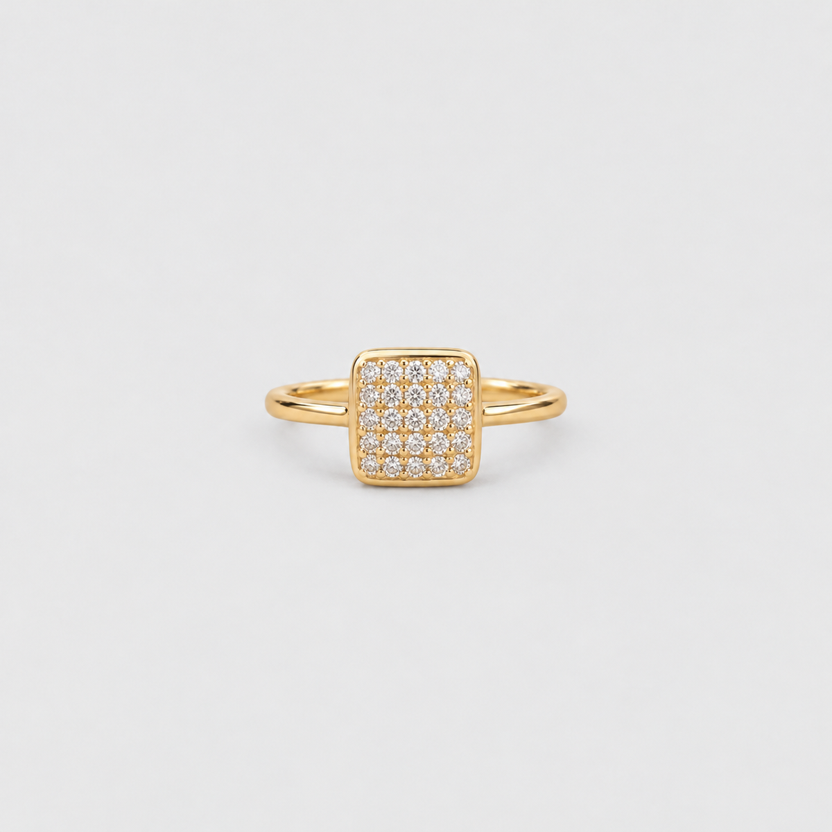A gold square ring featuring a pavé-set diamond center, photographed on a clean, light gray background.