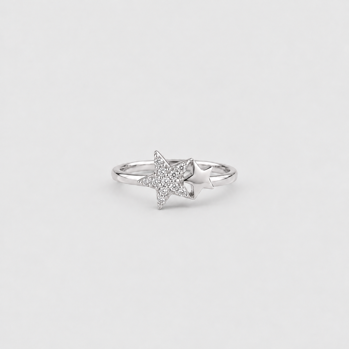 A silver ring featuring a star-shaped pavé setting with a smaller star layered behind it, shown on a light gray background.