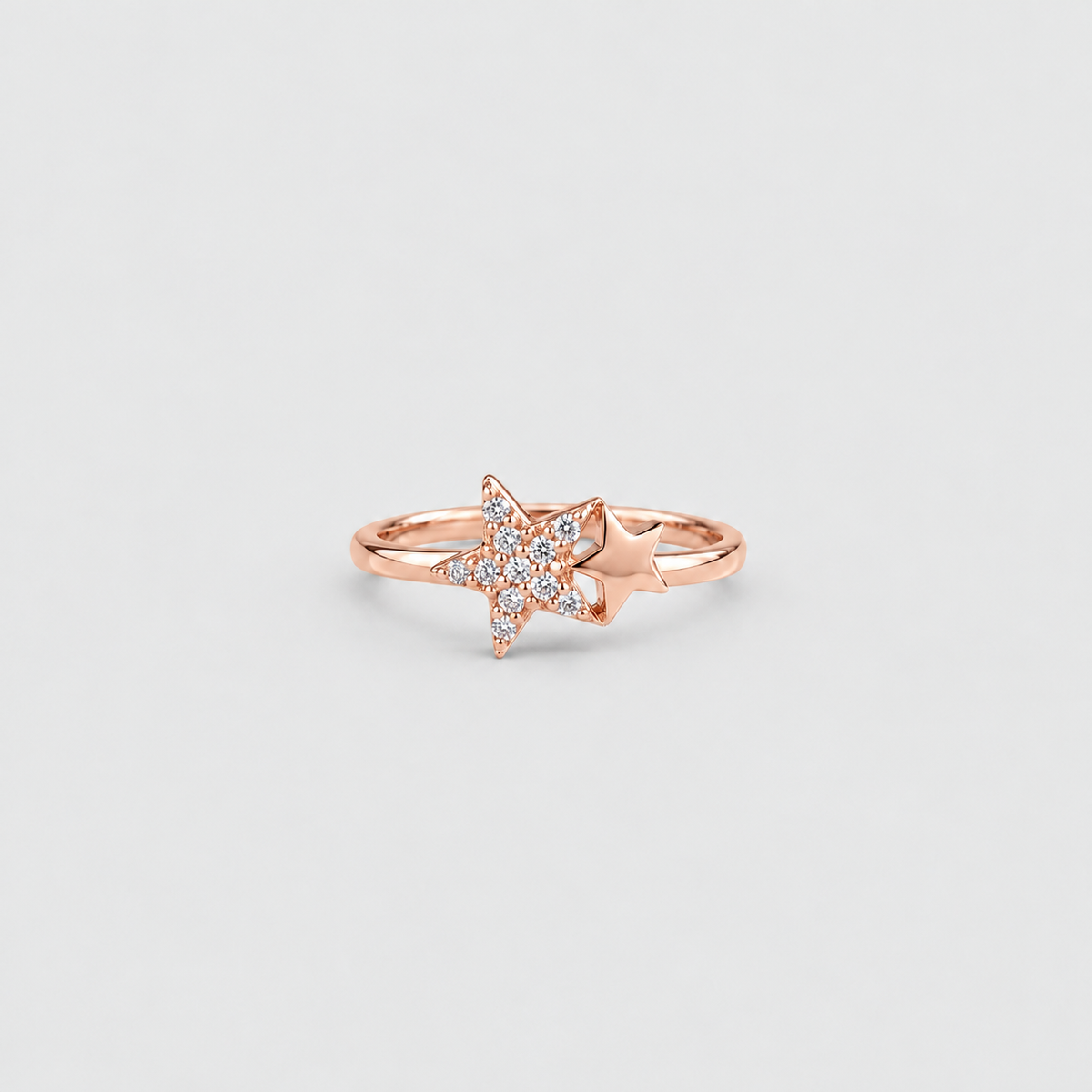 A rose gold ring featuring a star-shaped pavé diamond setting with a small star accent on the band, shown against a light gray background.