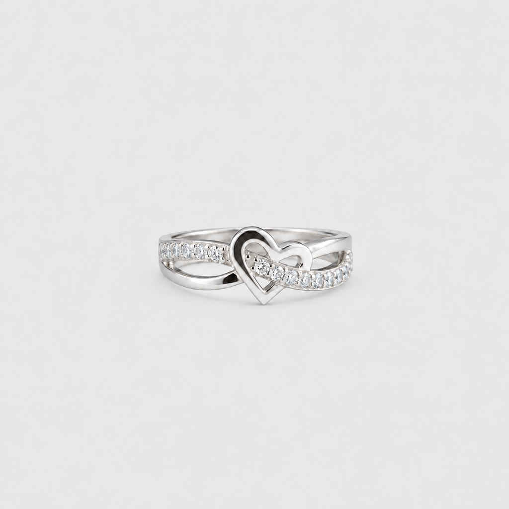 A silver ring featuring a central open heart design paved with small clear stones, set against a plain light gray background.