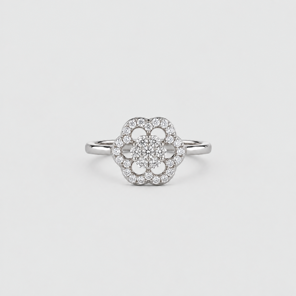 A silver-toned flower cluster ring with a central round diamond surrounded by a halo of smaller diamonds, set on a plain light gray background.