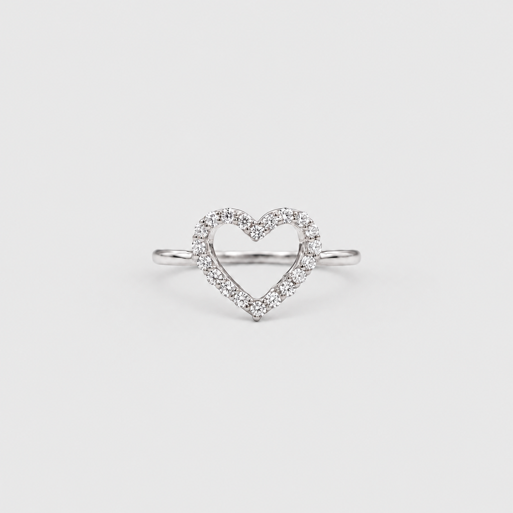 A silver heart-shaped ring with a pavé diamond border, photographed on a clean, light gray background.