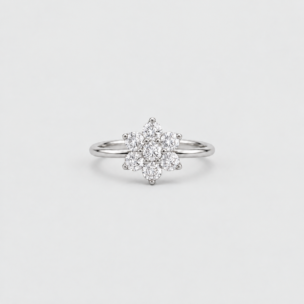 A silver-toned ring featuring a flower-shaped cluster of small clear gemstones on a plain light gray background.