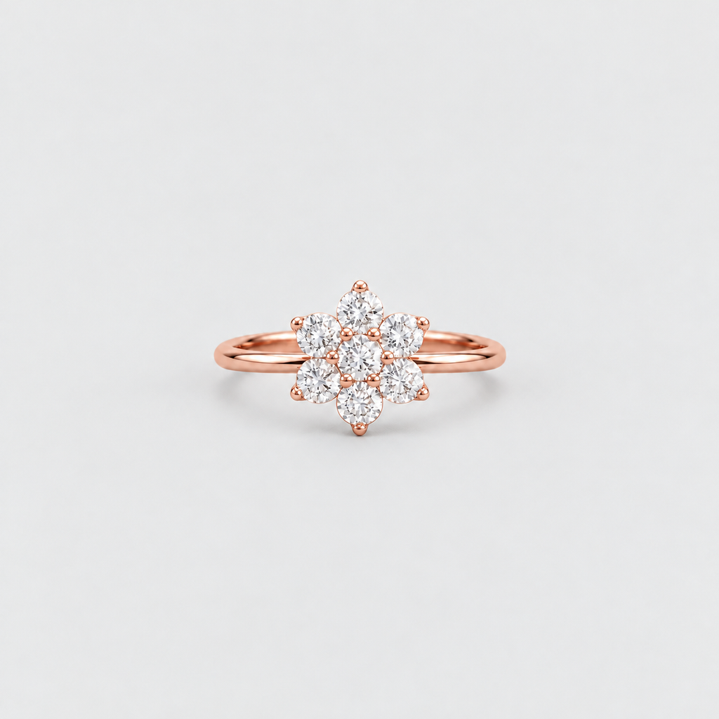 A rose gold ring with a flower-shaped cluster of clear gemstones, photographed on a clean, light gray background.